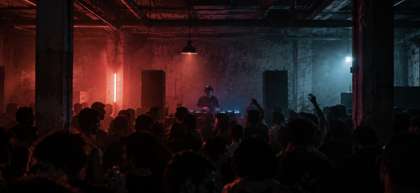 Underground electronic music party in a dim, unfinished warehouse space